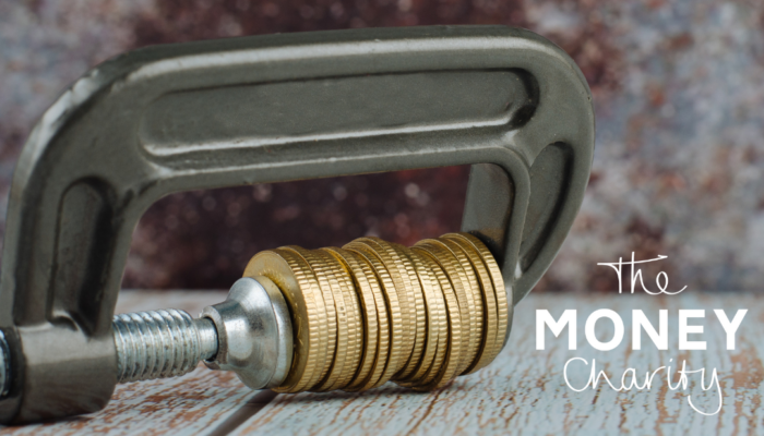 The Money Statistics March 2024 - Improving Signs Not Yet Enough to Lessen Household Squeeze - Image shows a pile of coins being held tightly in a vice grip.